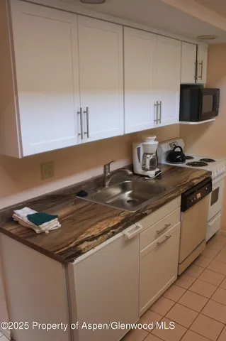 a kitchen with granite countertop a sink a stove and cabinets