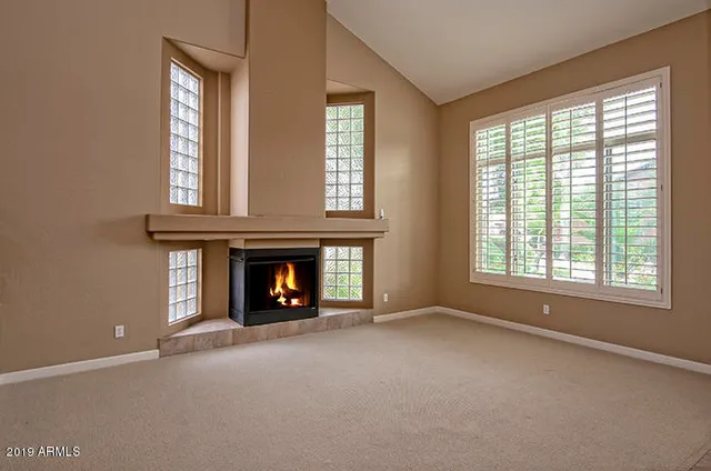 a view of an empty room with window and fire place