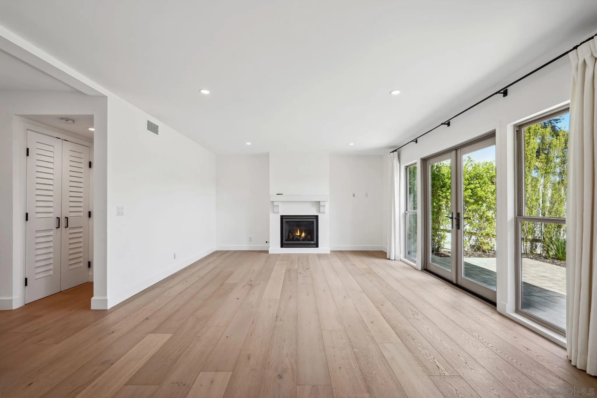 211 Via Osuna Rancho Santa Fe, CA 92091 - Photo 10 of 32 an empty room with wooden floor fireplace and windows
