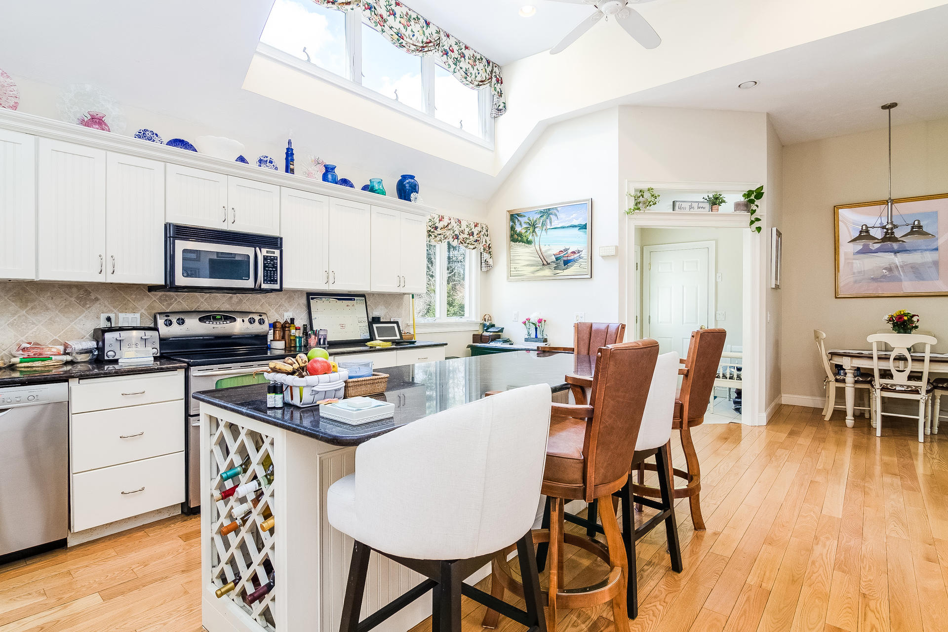 568 Santuit Road Cotuit, MA 02635 - Photo 14 of 30 a kitchen with stainless steel appliances granite countertop a stove top oven a sink a dining table and chairs with wooden floor