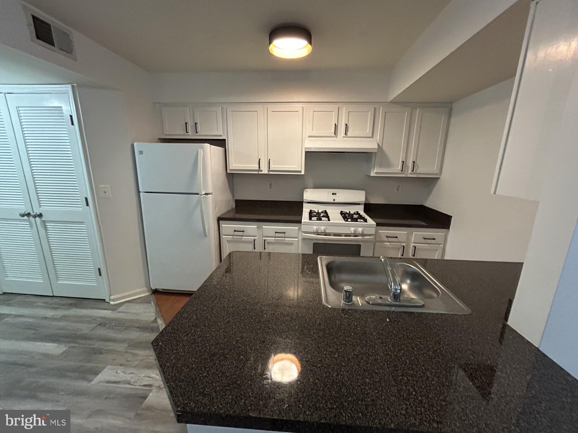 1700 W Street Southeast, Unit 5 Washington, DC 20020 - Photo 4 of 15 a kitchen with a refrigerator a stove a microwave and white cabinets