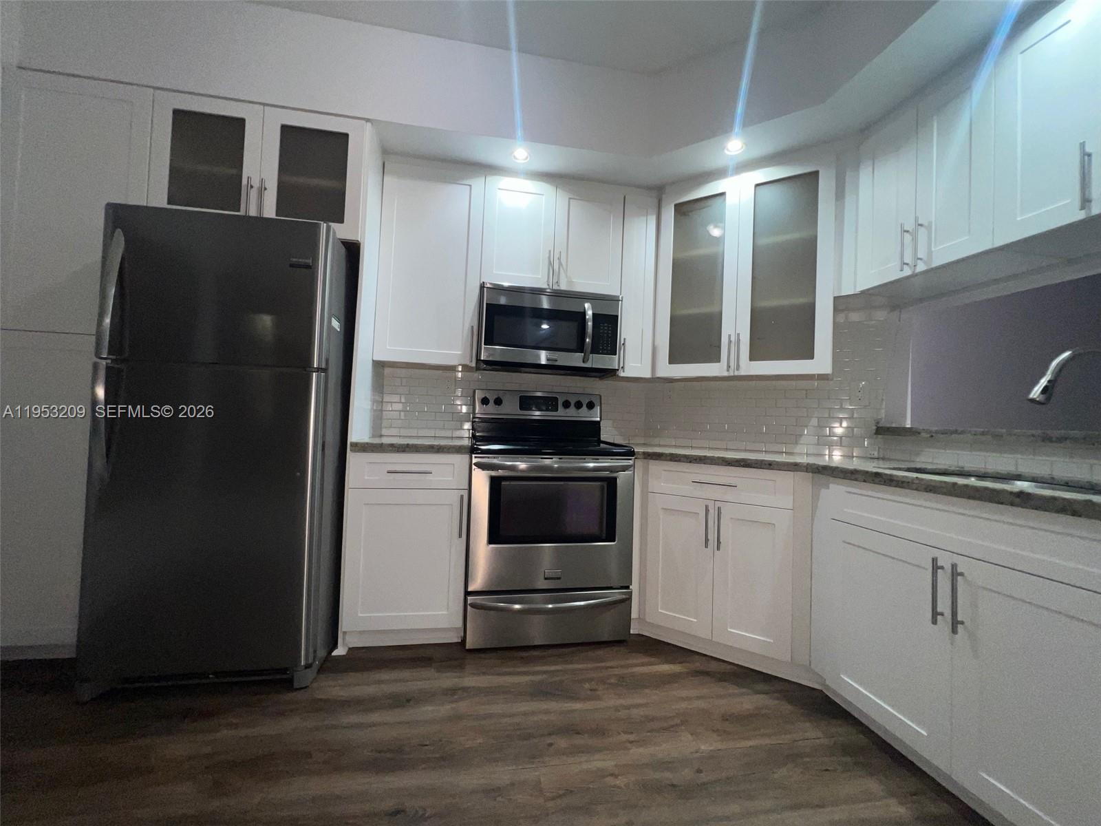 8831 Southwest 130th Place, Unit 106 Miami, FL 33186 - Photo 6 of 15 a kitchen with granite countertop a refrigerator and a stove top oven