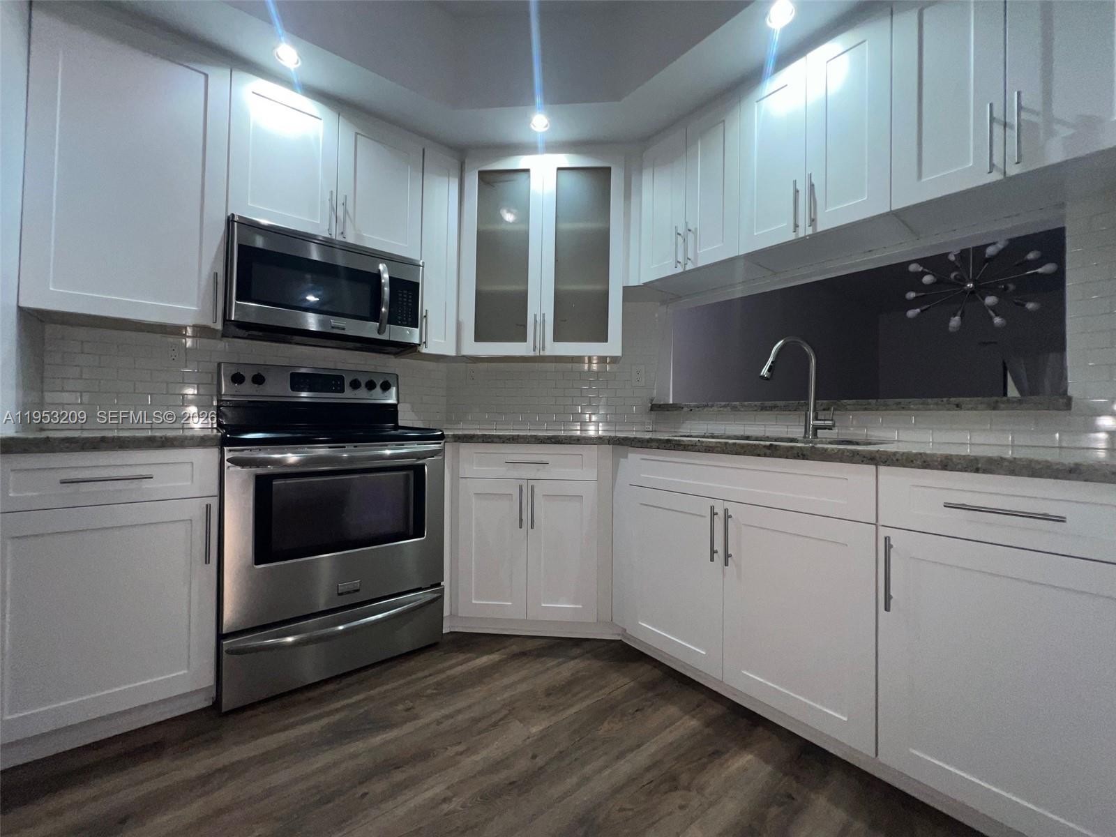 8831 Southwest 130th Place, Unit 106 Miami, FL 33186 - Photo 7 of 15 a kitchen with granite countertop white cabinets stainless steel appliances and a sink