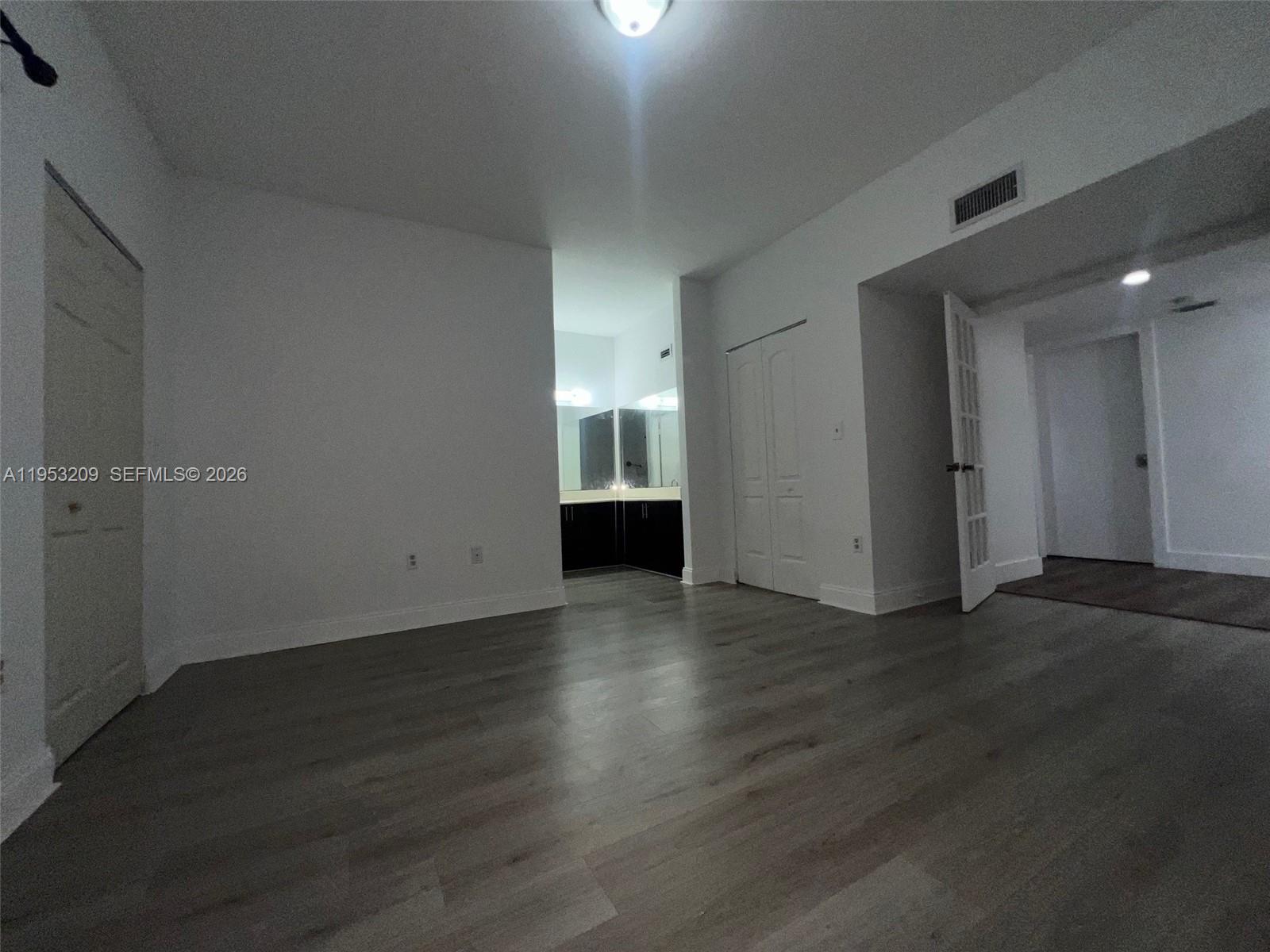 8831 Southwest 130th Place, Unit 106 Miami, FL 33186 - Photo 8 of 15 an empty room with wooden floor and windows