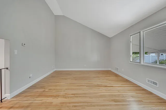 a view of an empty room with window and wooden floor