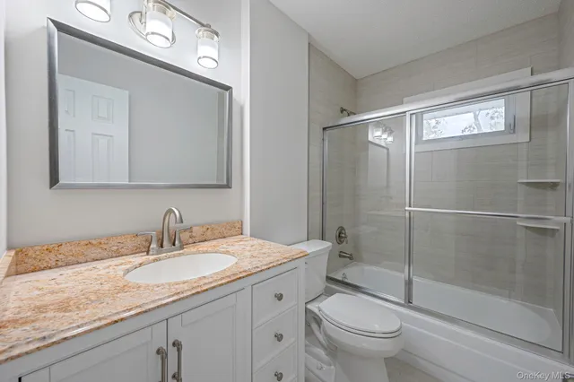 a bathroom with a granite countertop sink toilet a mirror and shower