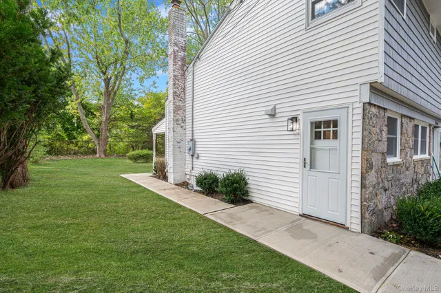 a view of a white house next to a yard and a large tree