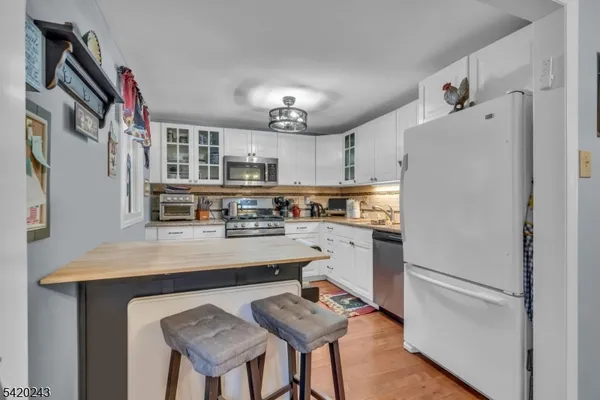 a kitchen with stainless steel appliances granite countertop a refrigerator a sink dishwasher a stove and a refrigerator with wooden floor