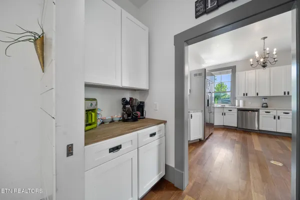 a kitchen with white cabinets and wooden floor