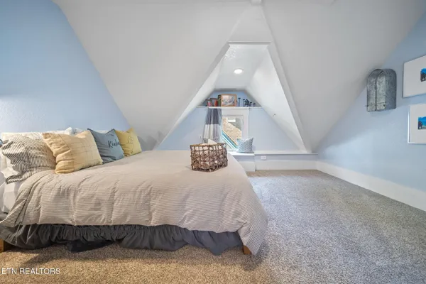 a bedroom with a bed and dresser with wooden floor