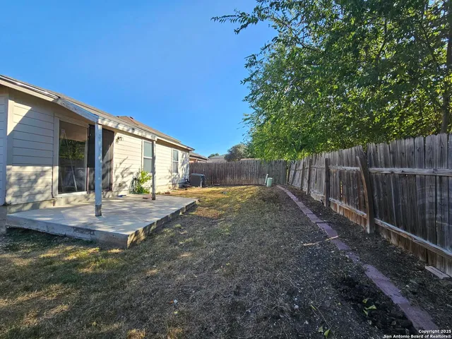 a view of backyard with wooden fence and trees