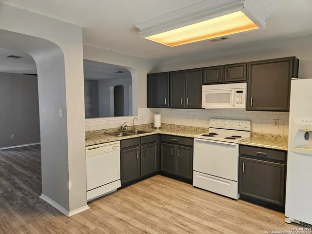 a kitchen with granite countertop a sink cabinets and stainless steel appliances