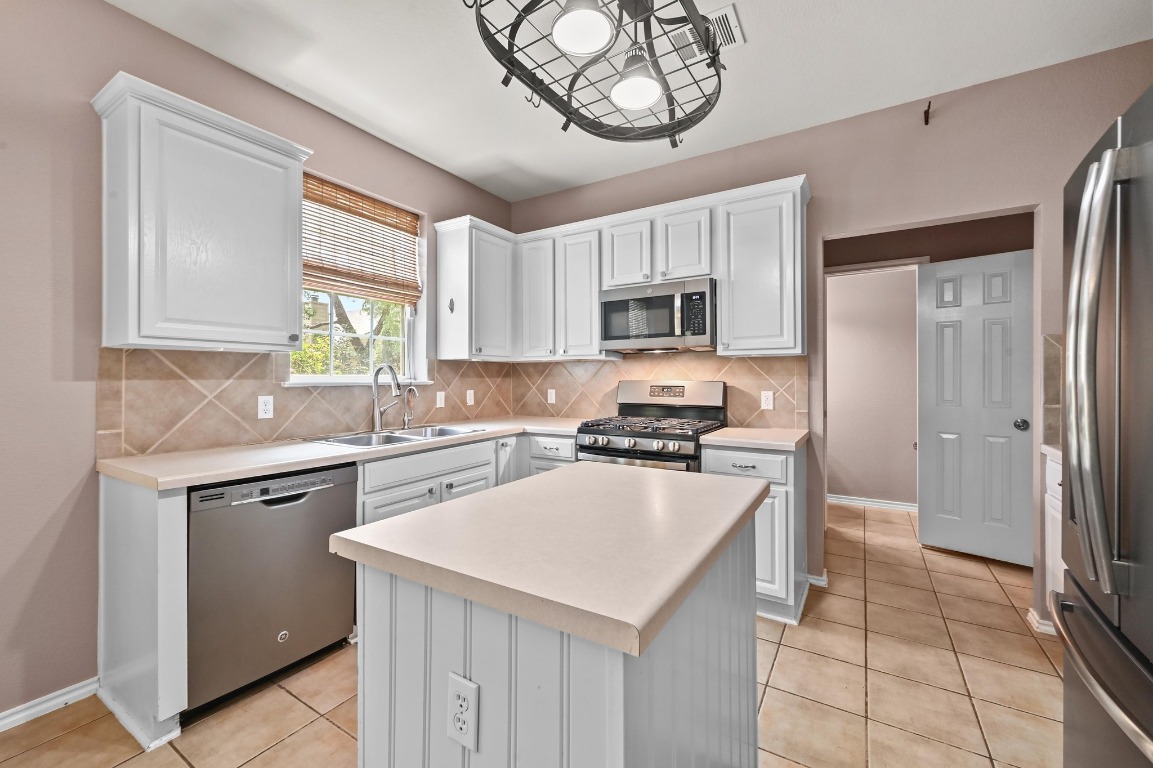 964 Hometown Parkway Kyle, TX 78640 - Photo 14 of 38 a kitchen with a sink a stove a refrigerator cabinets and a window