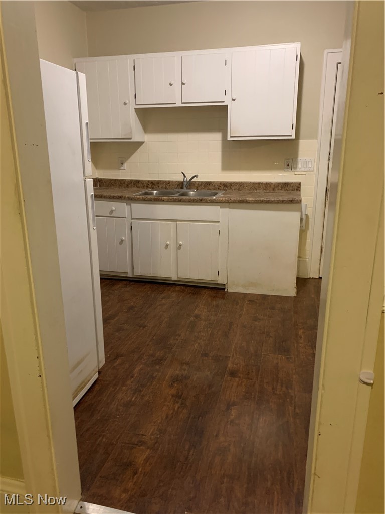 13000 Rockside Road Cleveland, OH 44125 - Photo 23 of 41 Kitchen featuring dark wood-type flooring, sink, decorative backsplash, white cabinetry, and refrigerator