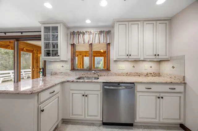 a kitchen with granite countertop white cabinets and a window