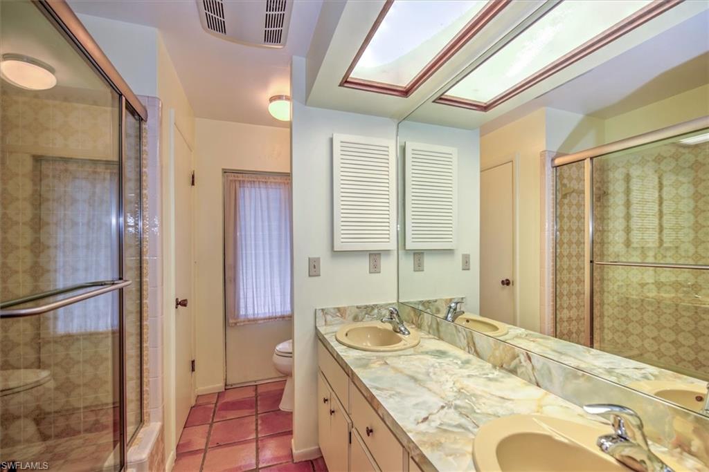 5960 Copper Leaf Lane Naples, FL 34116 - Photo 19 of 37 a bath room with a granite countertop sink and a large mirror