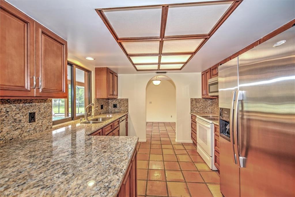 5960 Copper Leaf Lane Naples, FL 34116 - Photo 10 of 37 a kitchen with stainless steel appliances granite countertop a refrigerator and a sink