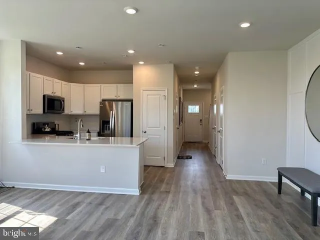 a kitchen with stainless steel appliances granite countertop a refrigerator oven a sink dishwasher and a stove with wooden floor