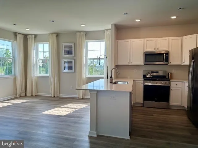 a kitchen with kitchen island granite countertop a stove top oven a sink and a granite counter top space