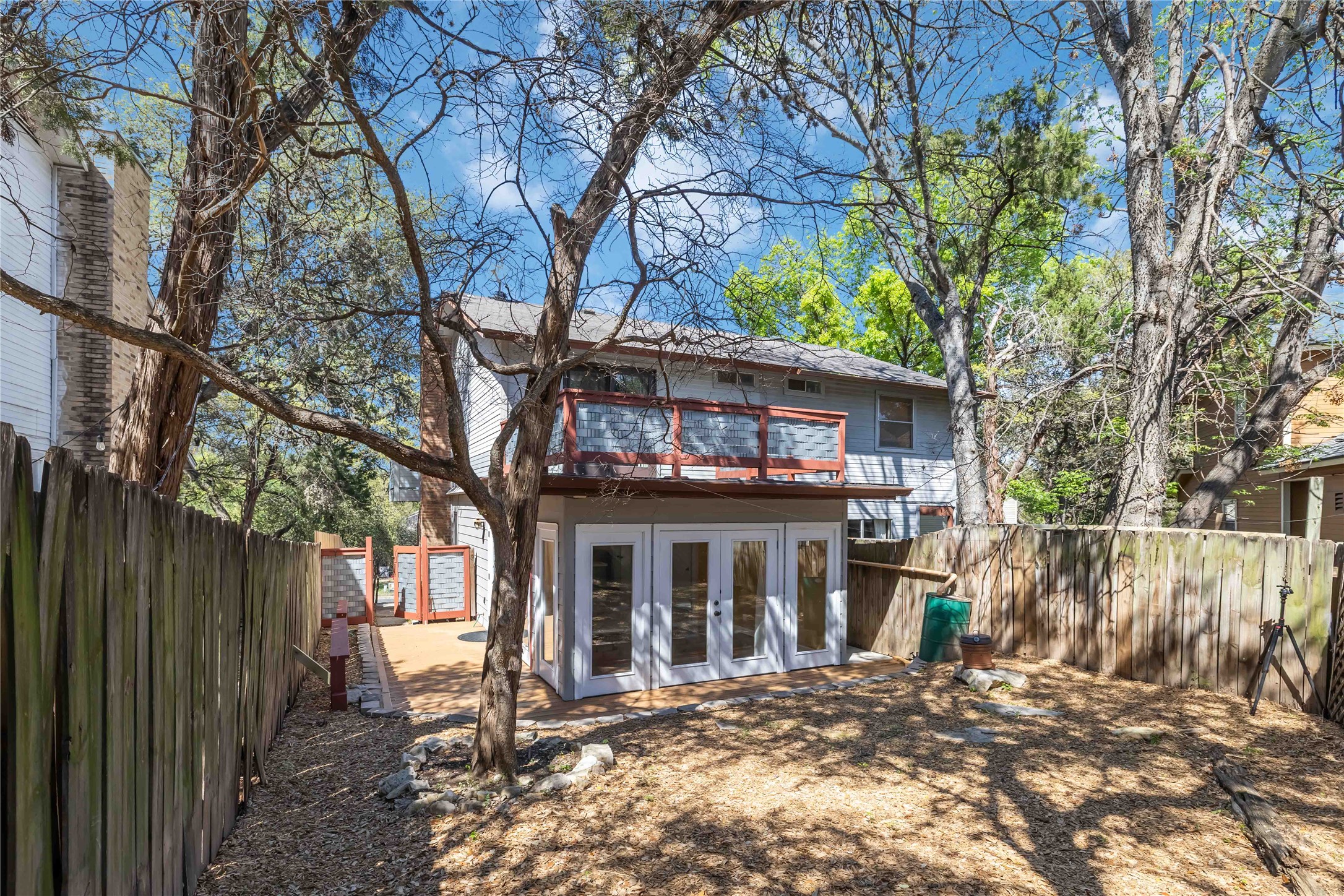 1703 Waterloo Trail, Unit B Austin, TX 78704 - Photo 29 of 36 Back of property with french doors, a fenced backyard, an outbuilding, a balcony, and a patio