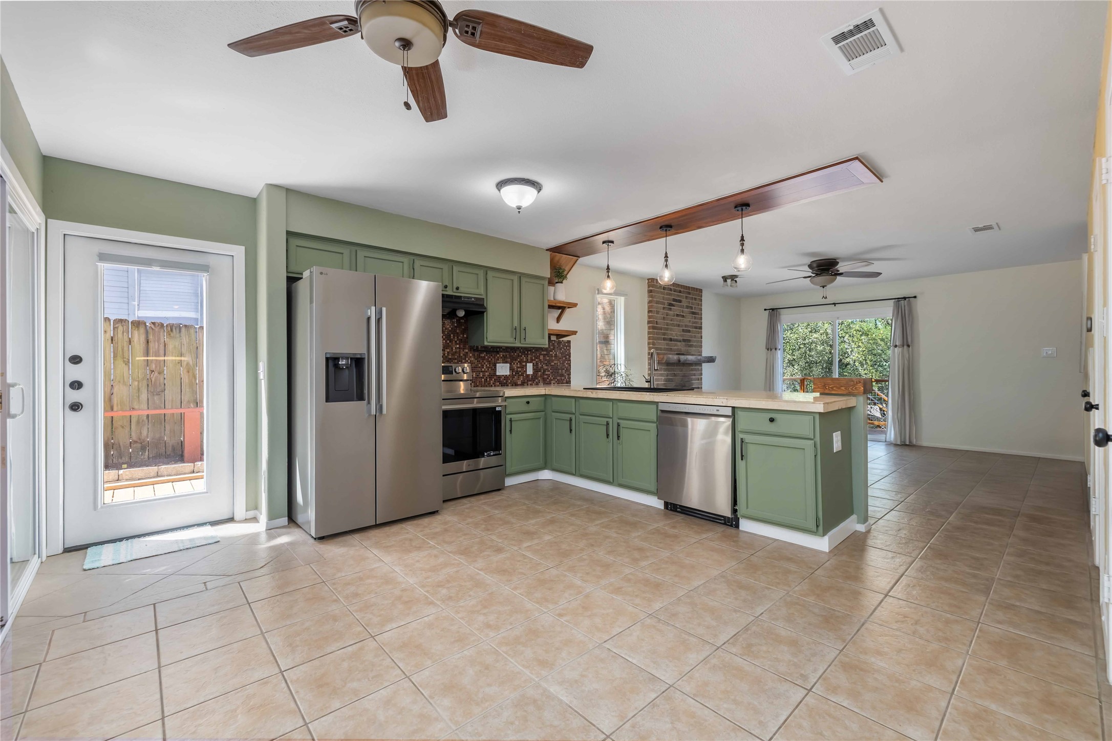 1703 Waterloo Trail, Unit B Austin, TX 78704 - Photo 7 of 36 Kitchen with green cabinets, ceiling fan, stainless steel appliances, light countertops, and a peninsula