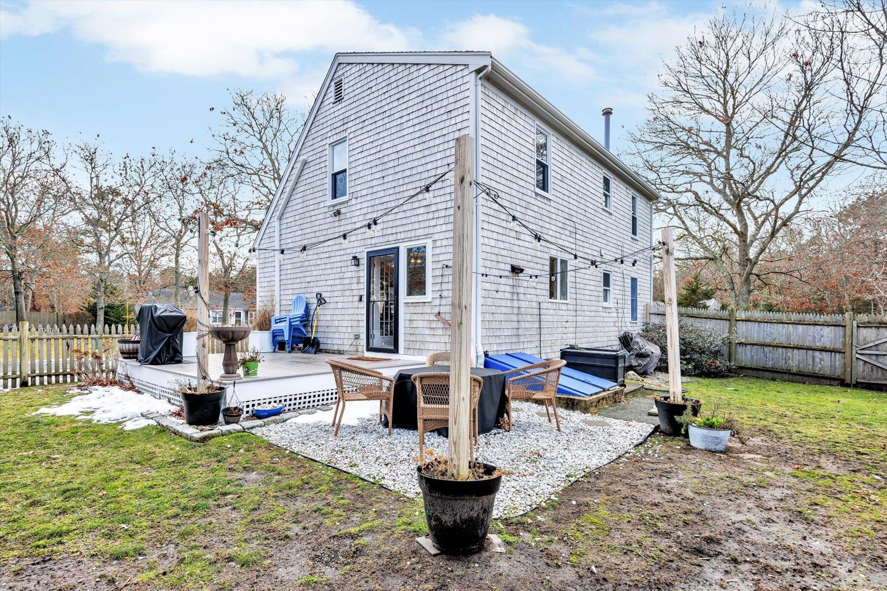 39 Papnomett Road Mashpee, MA 02649 - Photo 25 of 34 a view of a patio with couches chairs and a fire pit with wooden fence