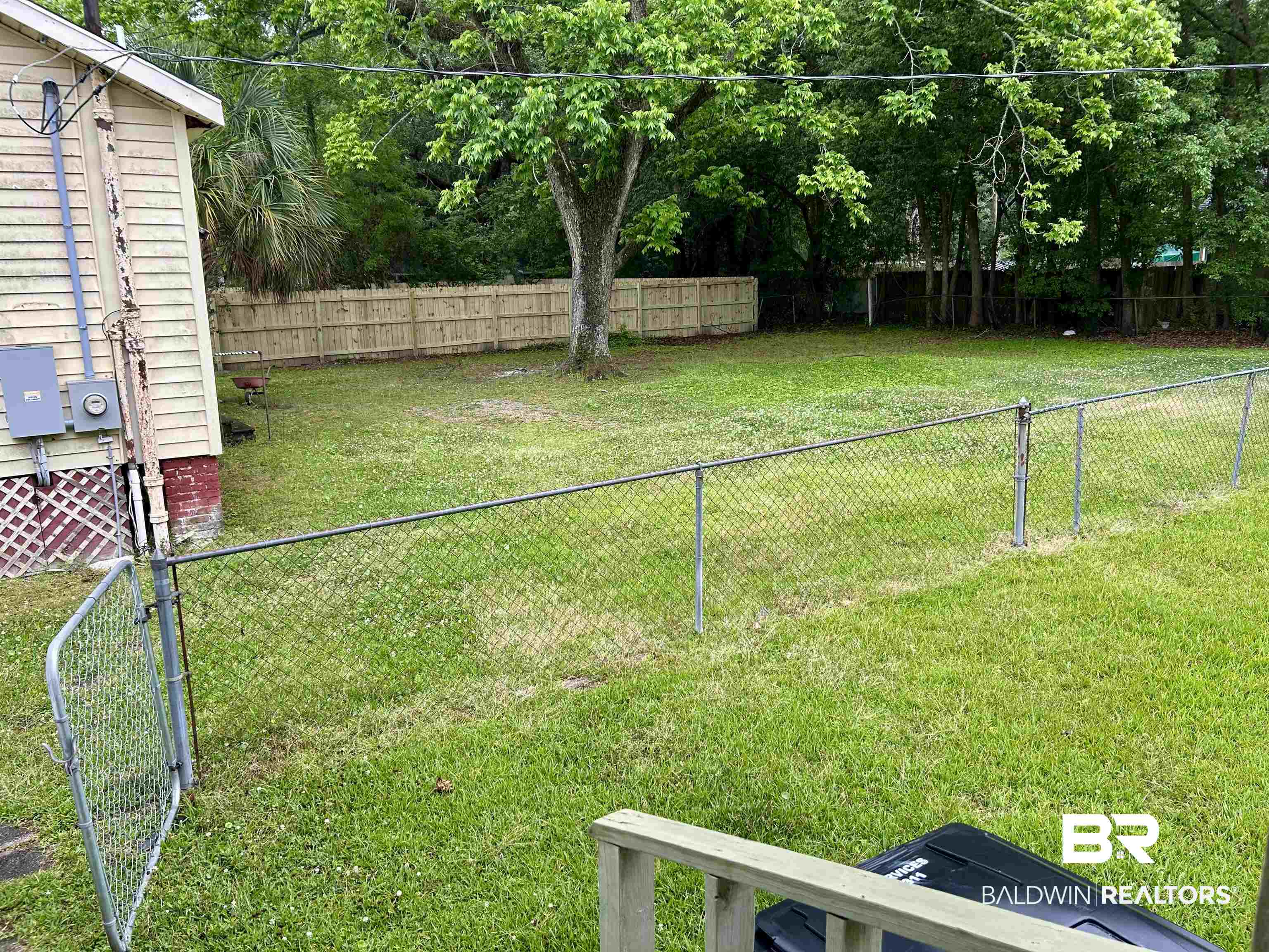 302 Stocking Street Mobile, AL 36604 - Photo 6 of 31 Expansive rear yard featuring a large grass area, mature trees, and a combination of chain-link and wood privacy fencing