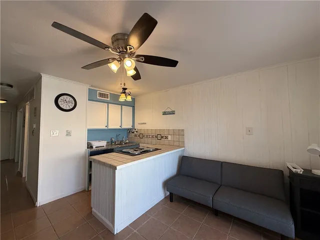 a kitchen with a sink a stove and a ceiling fan