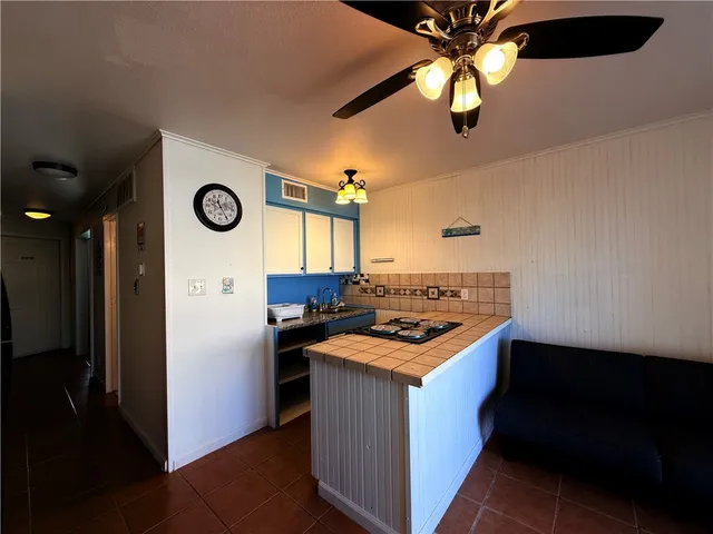 a kitchen with a stove and a refrigerator with a ceiling fan