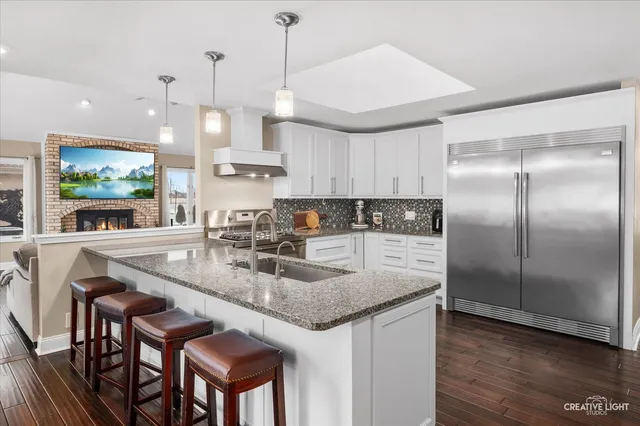 a kitchen with kitchen island granite countertop a sink a center island and stainless steel appliances