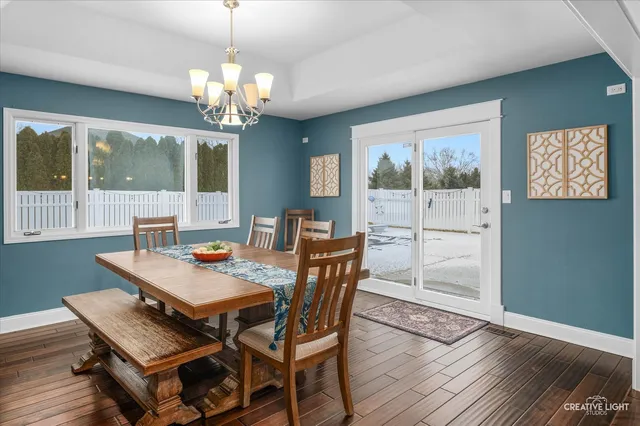 a dining room with wooden floor a chandelier a wooden table and chairs