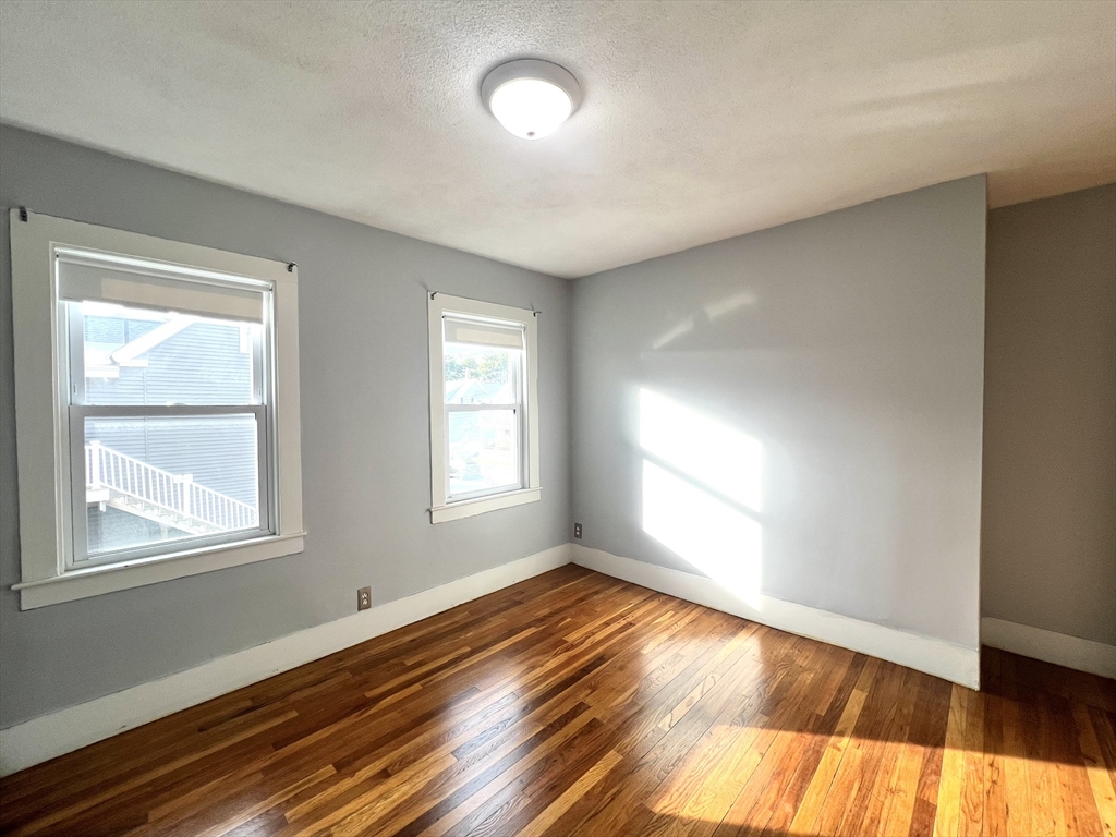 79 Franklin Street, Unit 2 Stoneham, MA 02180 - Photo 6 of 16 an empty room with wooden floor and windows