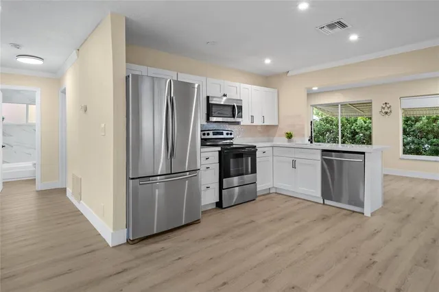 a kitchen with stainless steel appliances granite countertop a refrigerator and a stove top oven
