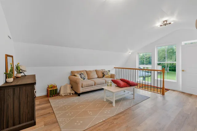 a living room with furniture a rug plants and a window