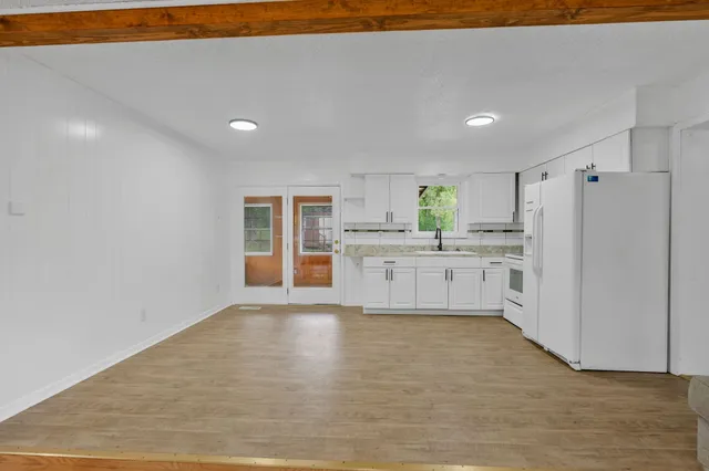 a large kitchen with a refrigerator a stove top oven and white cabinets