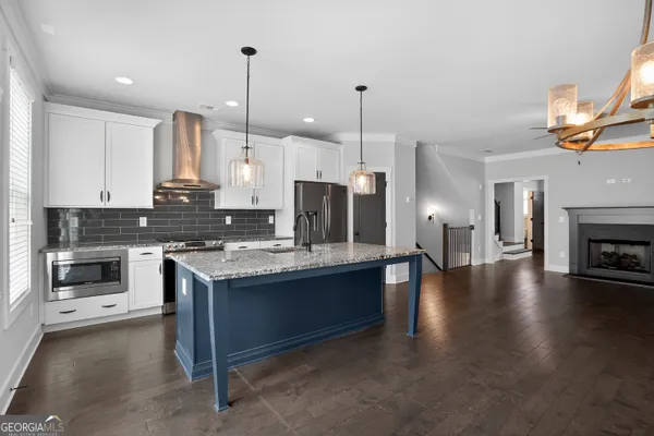 a kitchen with kitchen island granite countertop a stove and a wooden floor