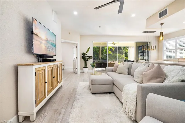 a living room with furniture a flat screen tv and a chandelier