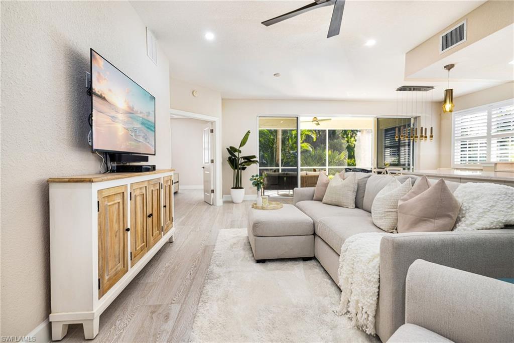 a living room with furniture a flat screen tv and a chandelier