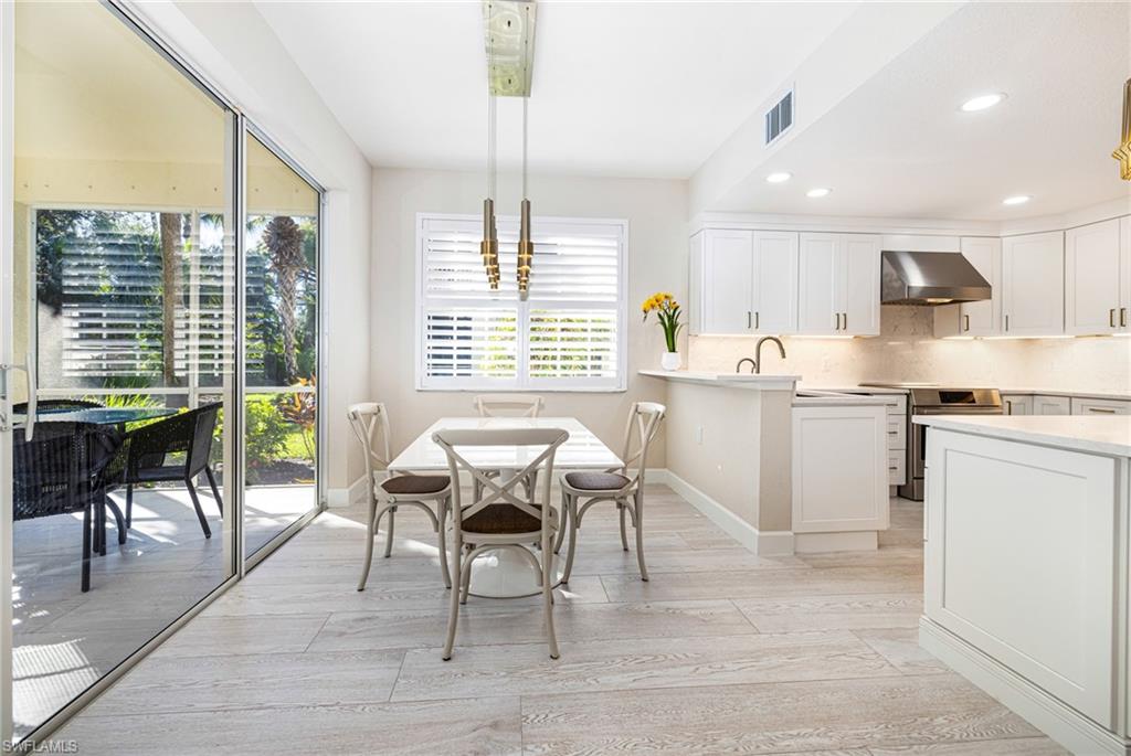 19071 Ridgepoint Drive, Unit 102 Estero, FL 33928 - Photo 13 of 50 a kitchen with granite countertop a table chairs sink and cabinets