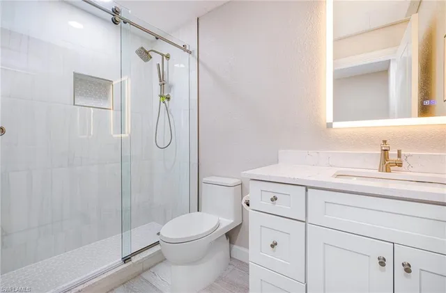 a bathroom with a granite countertop sink a toilet and shower
