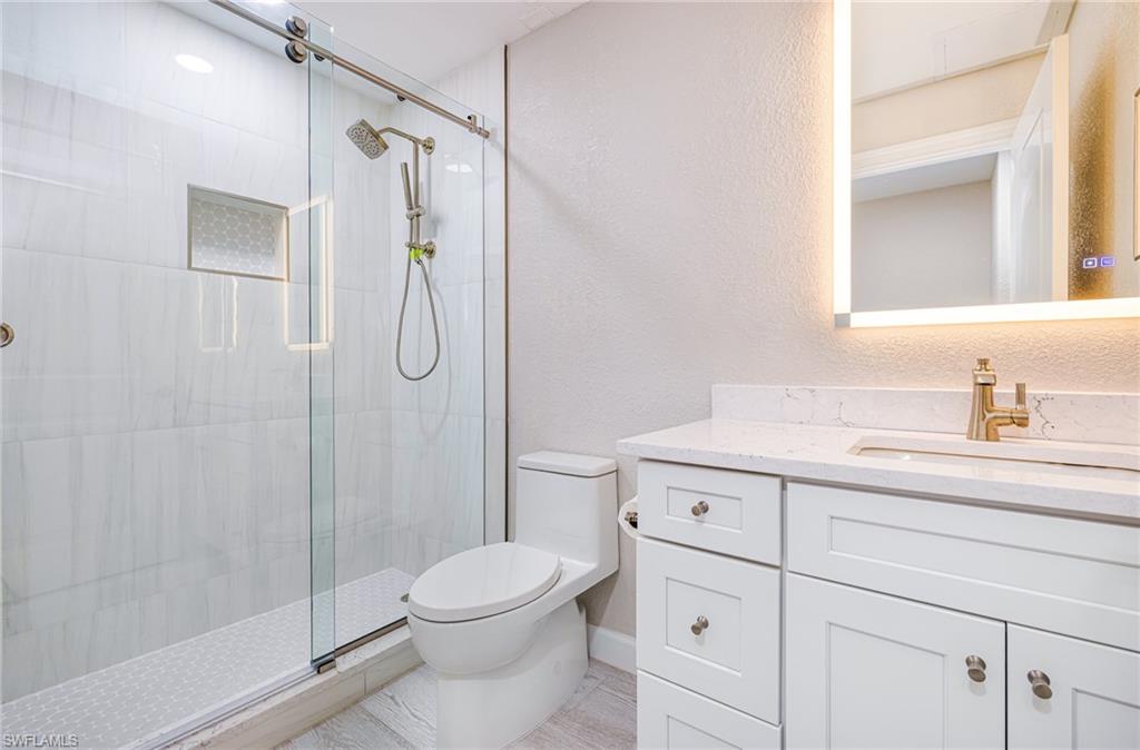 19071 Ridgepoint Drive, Unit 102 Estero, FL 33928 - Photo 27 of 50 a bathroom with a granite countertop sink a toilet and shower