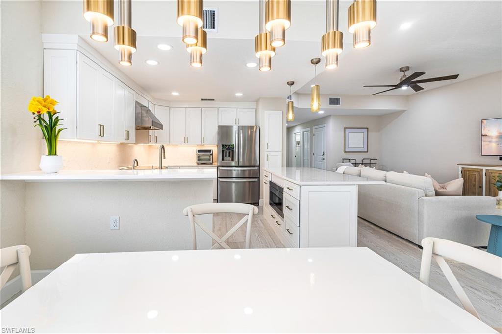 19071 Ridgepoint Drive, Unit 102 Estero, FL 33928 - Photo 10 of 50 a kitchen with kitchen island a white counter top space a sink stainless steel appliances and cabinets