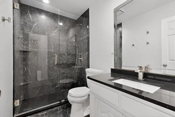 a bathroom with a granite countertop sink a toilet and shower