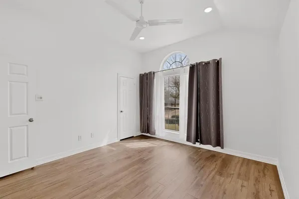 an empty room with wooden floor and windows