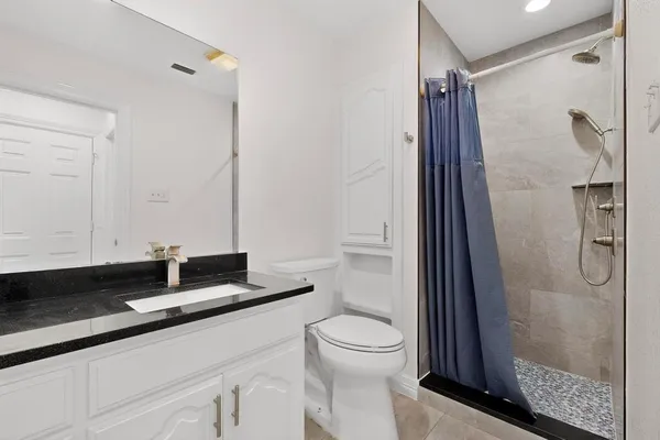 a bathroom with a granite countertop sink a toilet and shower