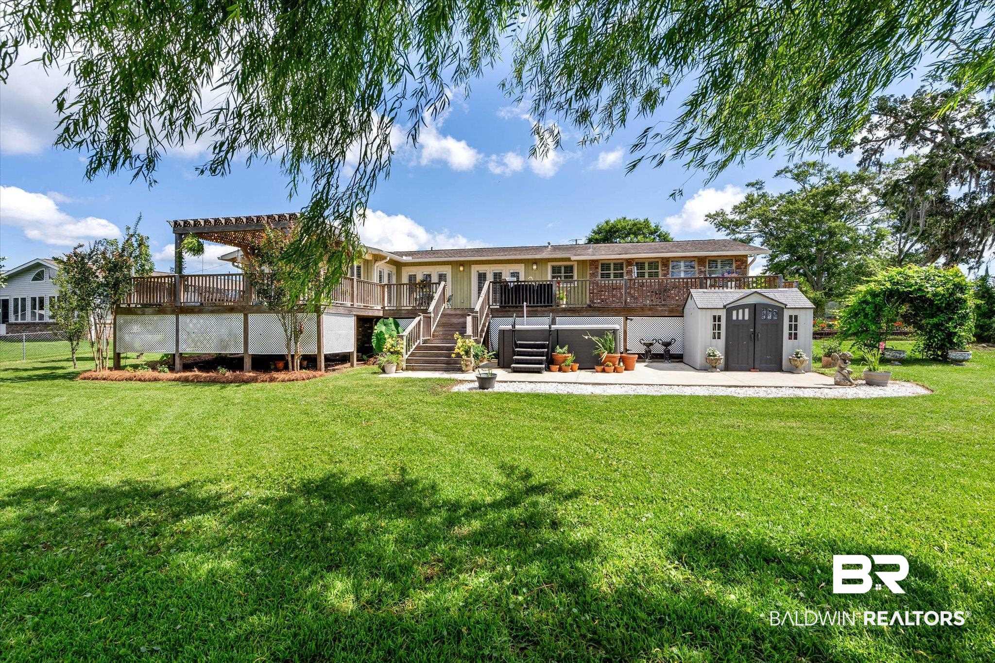 3801 Point Road Mobile, AL 36619 - Photo 39 of 55 Expansive backyard featuring a manicured lawn, a multi-level wooden deck with a pergola, a ground-level concrete patio, and a utility shed