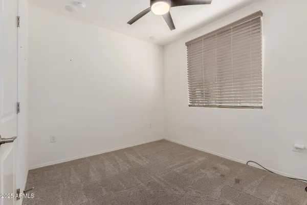 an empty room with a ceiling fan and a window