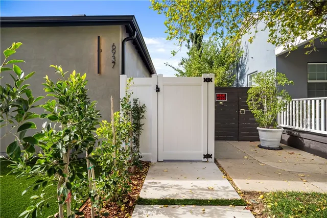 a kitchen with stainless steel appliances granite countertop a sink a stove a refrigerator and white cabinets with wooden floor