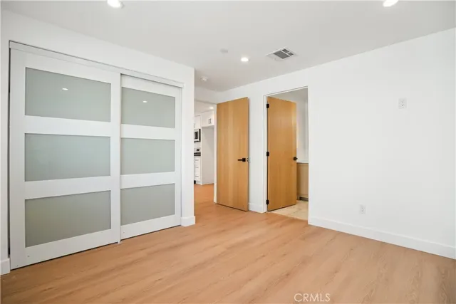 a view of an empty room with wooden floor and closet