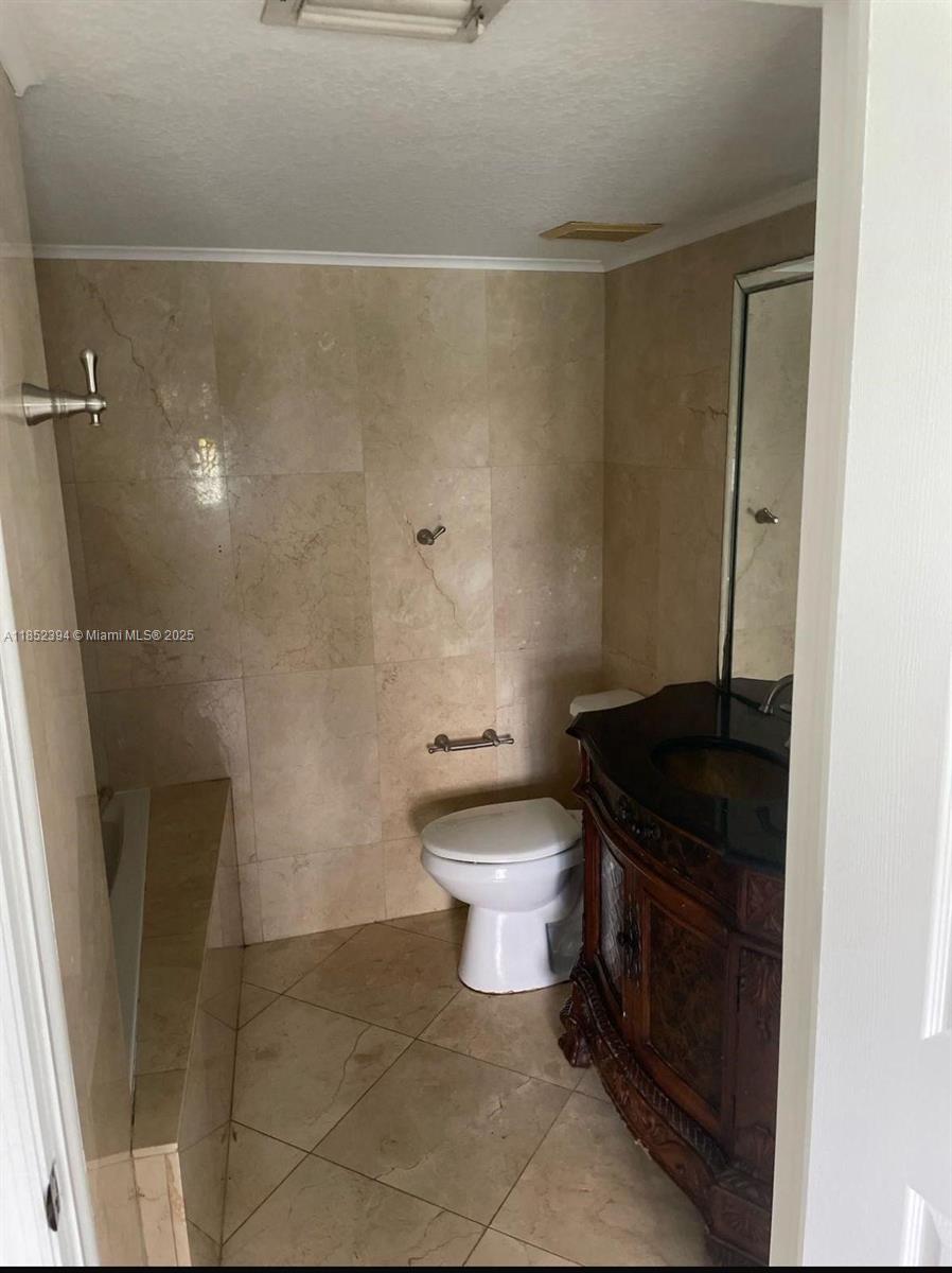 2701 Southeast 12th Road, Unit 106 Homestead, FL 33035 - Photo 20 of 21 a bathroom with a granite countertop toilet a sink and a shower